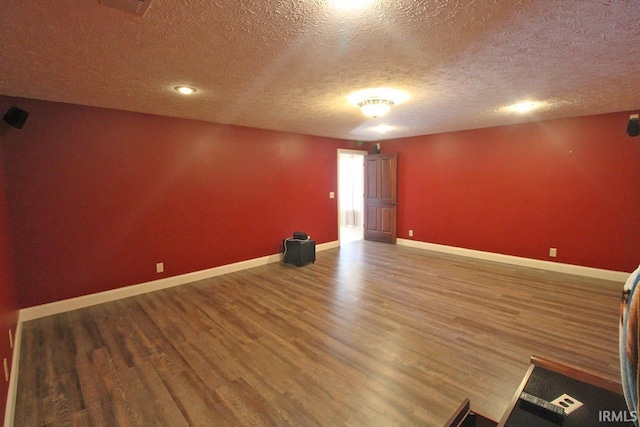 spare room featuring a textured ceiling, baseboards, and wood finished floors