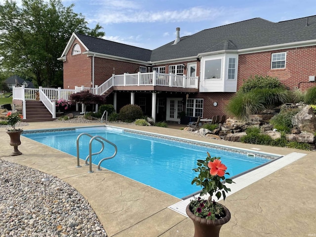 outdoor pool featuring stairs and a wooden deck