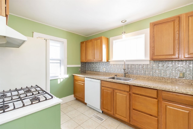 kitchen with white appliances, decorative backsplash, under cabinet range hood, pendant lighting, and a sink