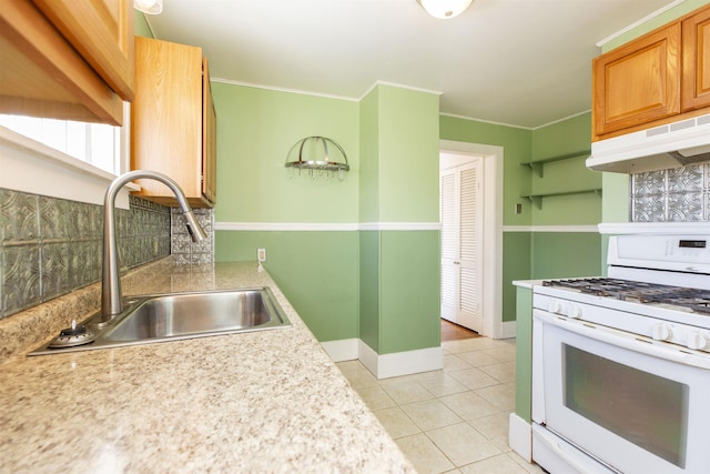 kitchen with light tile patterned floors, under cabinet range hood, a sink, light countertops, and white gas range