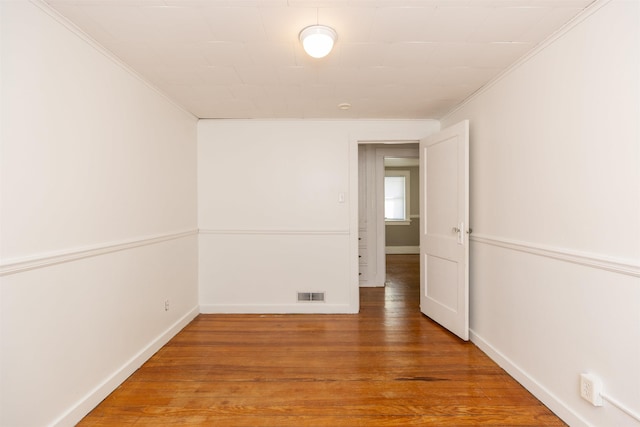 spare room with visible vents, baseboards, and wood finished floors