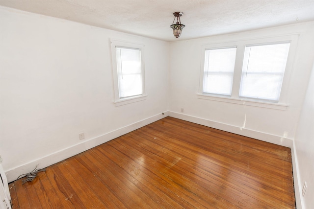 spare room with a healthy amount of sunlight, baseboards, and wood finished floors