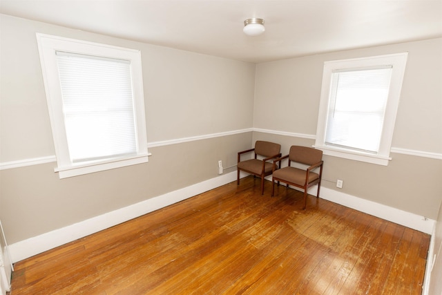 unfurnished room with wood finished floors, a wealth of natural light, and baseboards