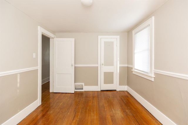 unfurnished bedroom with visible vents, dark wood finished floors, and baseboards