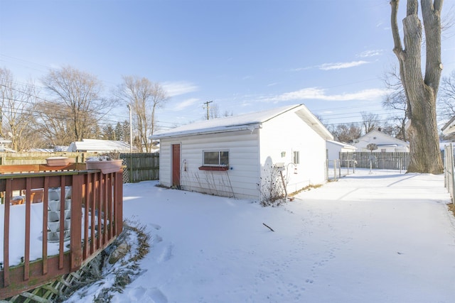 snow covered structure with an outbuilding and fence