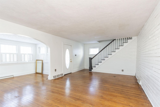 foyer featuring a textured ceiling, wood finished floors, visible vents, baseboards, and stairway