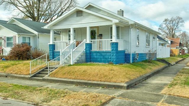 bungalow-style house featuring covered porch and a chimney