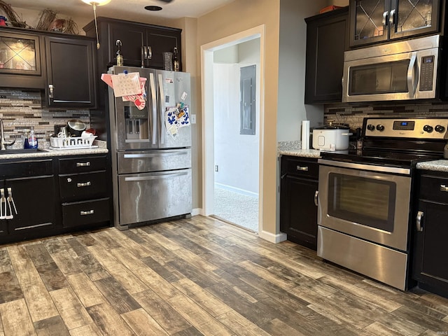 kitchen with backsplash, wood finished floors, light countertops, stainless steel appliances, and a sink