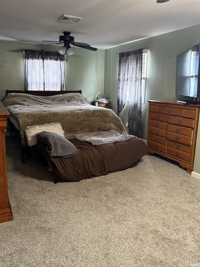 carpeted bedroom featuring visible vents and a ceiling fan