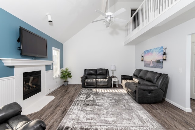 living area featuring baseboards, a tile fireplace, ceiling fan, wood finished floors, and high vaulted ceiling