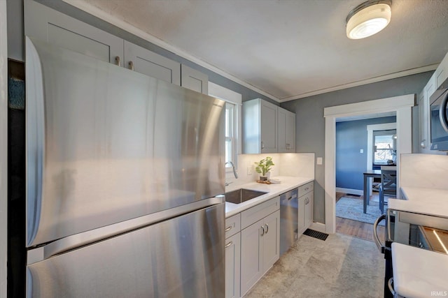 kitchen with stainless steel appliances, a sink, light countertops, backsplash, and crown molding