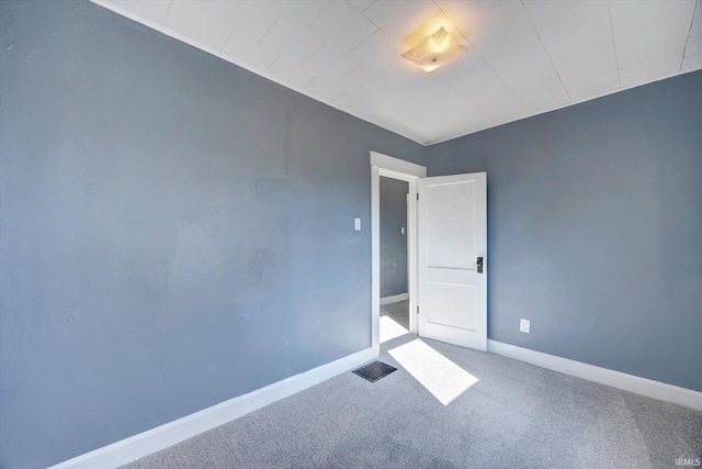 carpeted spare room with visible vents and baseboards