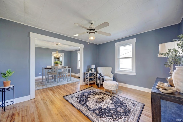 sitting room featuring ceiling fan with notable chandelier, wood finished floors, and baseboards