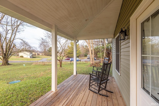 wooden deck featuring covered porch and a yard