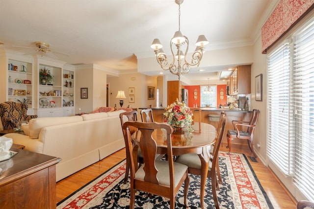 dining room with light wood-style floors, ornamental molding, and ceiling fan with notable chandelier