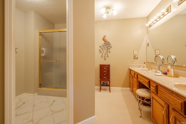 full bathroom featuring double vanity, a stall shower, baseboards, marble finish floor, and a sink