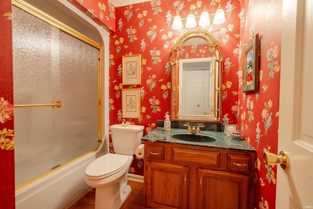 full bath featuring toilet, wallpapered walls, shower / bath combination with glass door, and vanity