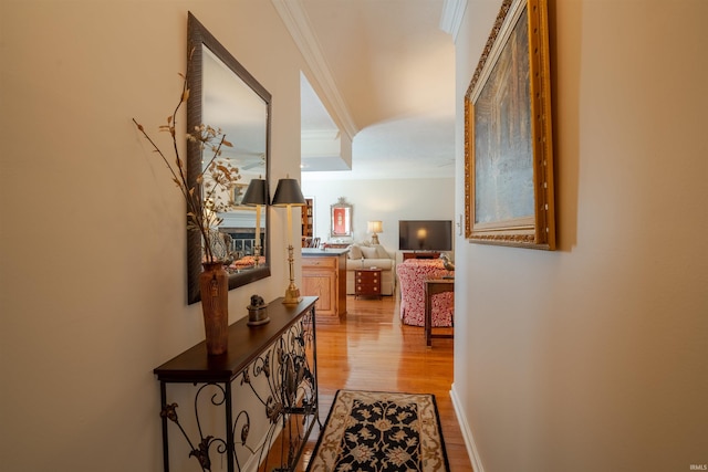 hall featuring light wood-style floors, baseboards, and crown molding