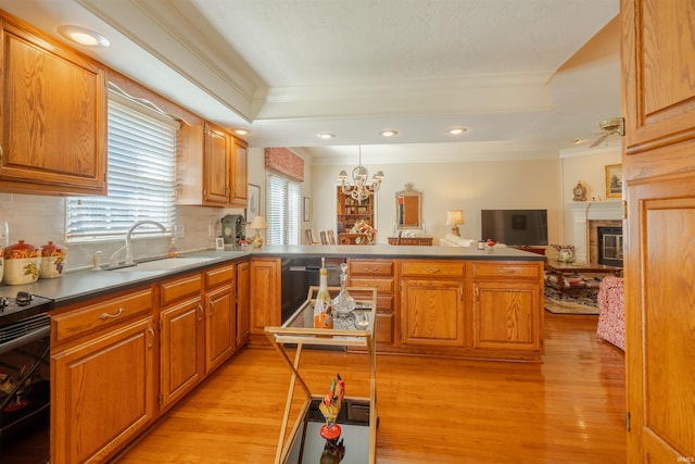 kitchen with open floor plan, a peninsula, dark countertops, and a sink