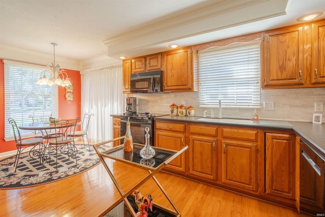 kitchen featuring brown cabinetry, dark countertops, a sink, and black appliances