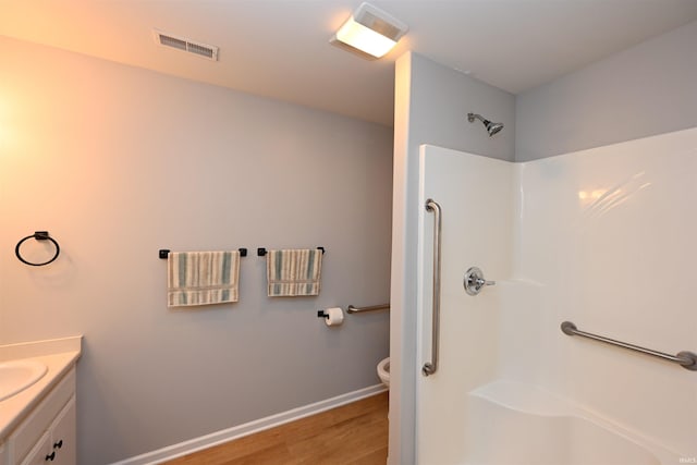 full bath featuring a shower, visible vents, toilet, wood finished floors, and baseboards