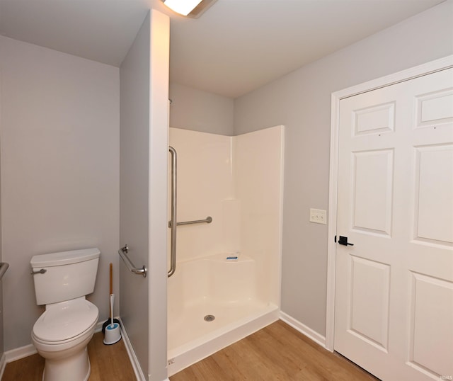 bathroom featuring baseboards, a shower stall, toilet, and wood finished floors