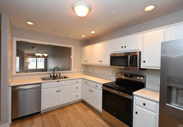 kitchen featuring stainless steel appliances, a sink, white cabinets, light countertops, and pendant lighting