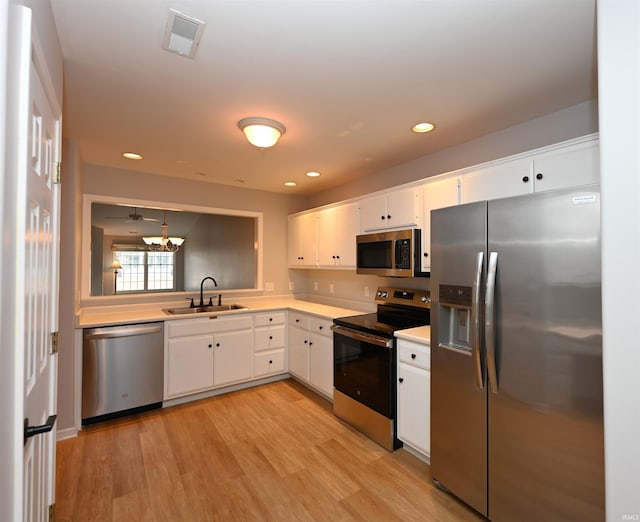 kitchen with light countertops, visible vents, appliances with stainless steel finishes, white cabinetry, and a sink