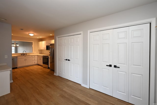 kitchen featuring electric range, wood finished floors, a sink, light countertops, and dishwasher