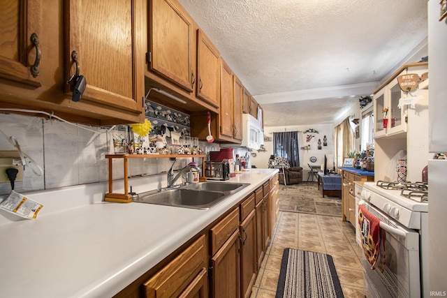 kitchen with white appliances, brown cabinets, light countertops, a textured ceiling, and a sink