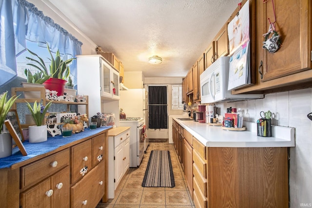 kitchen featuring light countertops, white appliances, and brown cabinets