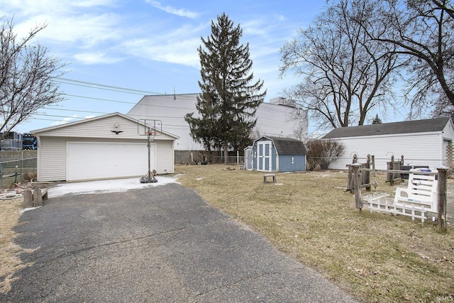 exterior space with a storage shed, a detached garage, fence, an outdoor structure, and a front lawn