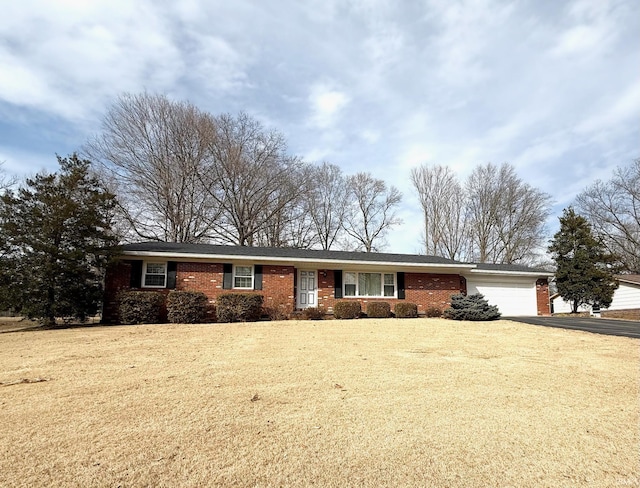 ranch-style home with aphalt driveway, a front yard, brick siding, and an attached garage