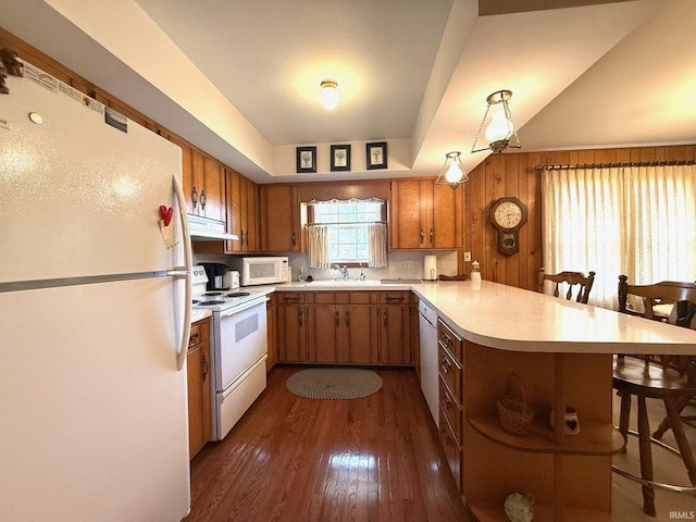 kitchen featuring brown cabinetry, white appliances, light countertops, and a peninsula