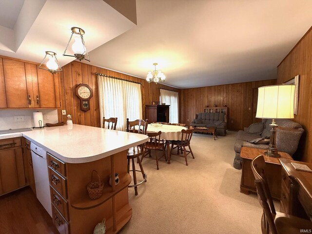 kitchen with decorative light fixtures, light countertops, open floor plan, dishwasher, and a peninsula