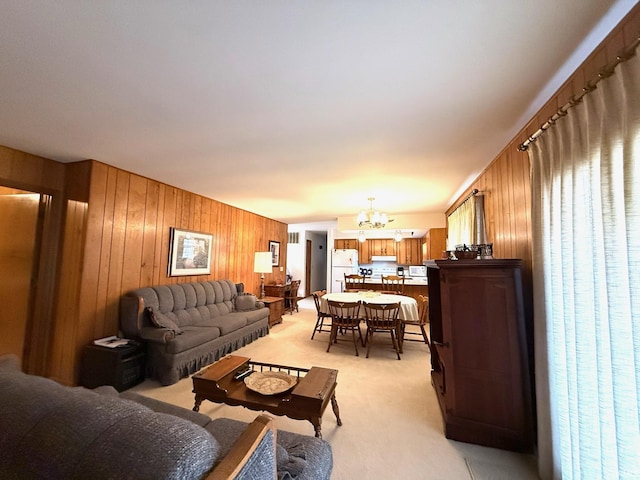 living area featuring light carpet, wooden walls, and a notable chandelier