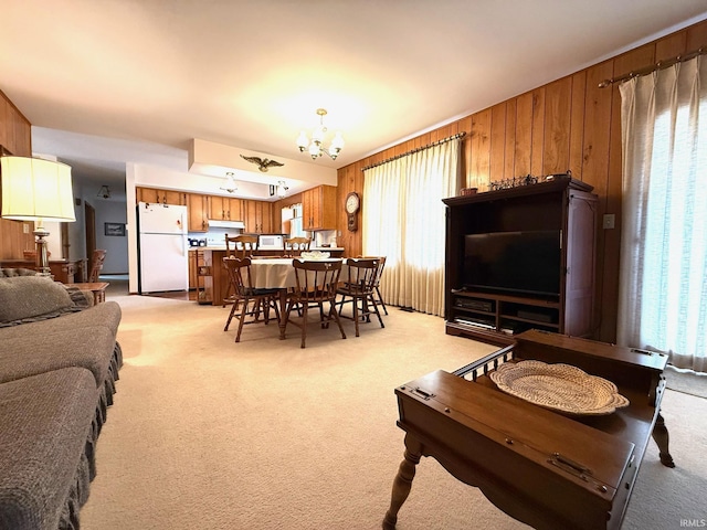 dining area featuring a healthy amount of sunlight, light carpet, wooden walls, and an inviting chandelier