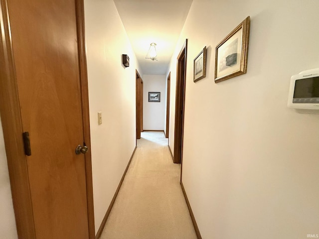 hall featuring light carpet and baseboards