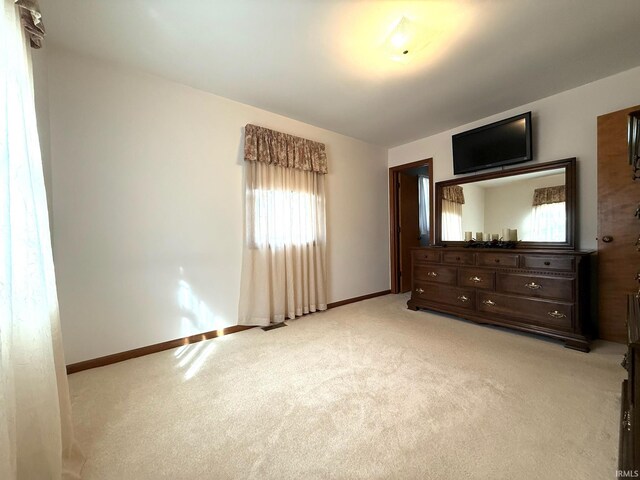 unfurnished bedroom with light carpet and baseboards