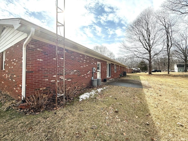 view of side of property with a lawn and brick siding