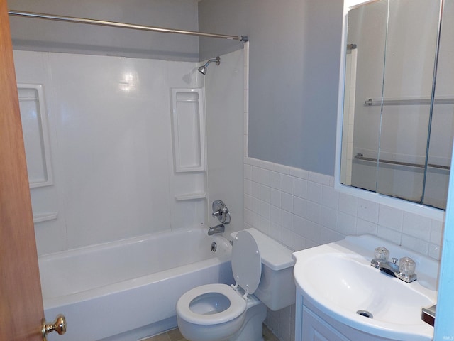 bathroom with toilet, a wainscoted wall, vanity, tile walls, and shower / washtub combination