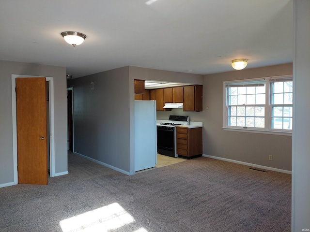 kitchen with range with gas stovetop, light countertops, freestanding refrigerator, light carpet, and under cabinet range hood