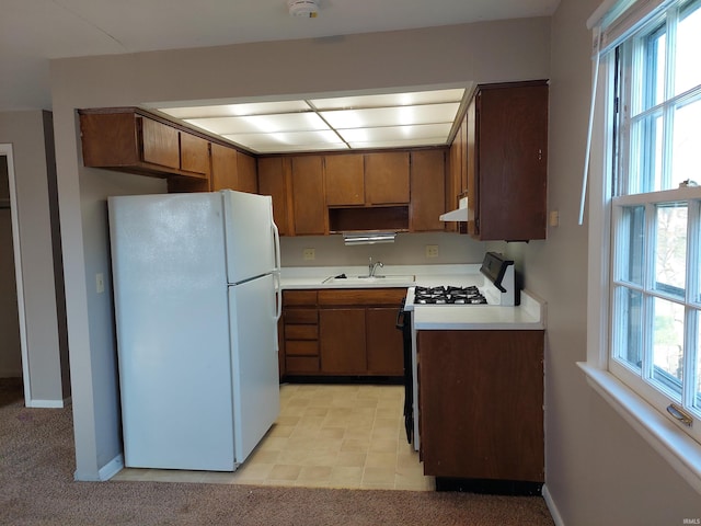 kitchen with a wealth of natural light, light countertops, range with gas stovetop, and freestanding refrigerator