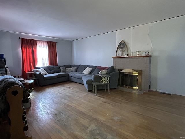 living area featuring wood-type flooring, a fireplace with flush hearth, and visible vents