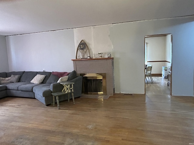 living area with a brick fireplace and wood finished floors