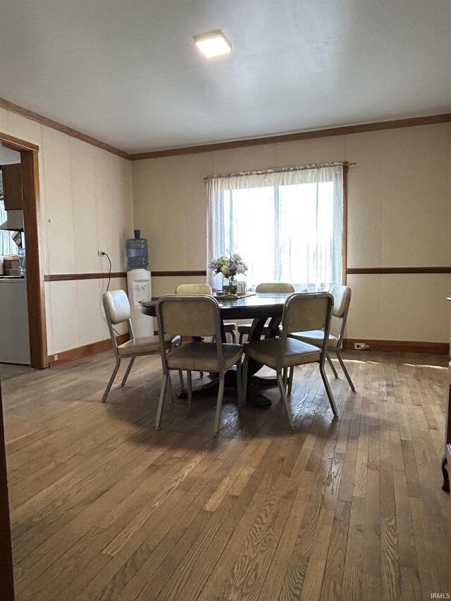 dining room featuring ornamental molding, hardwood / wood-style flooring, and baseboards