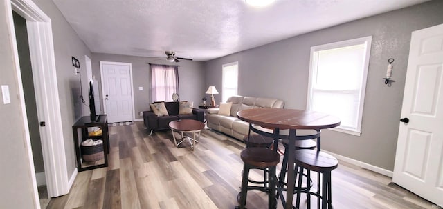 living room featuring light wood finished floors, a ceiling fan, and baseboards