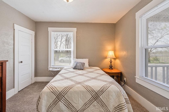 carpeted bedroom featuring a textured wall and baseboards