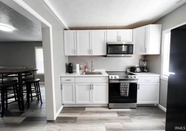 kitchen featuring light countertops, appliances with stainless steel finishes, a sink, and white cabinetry