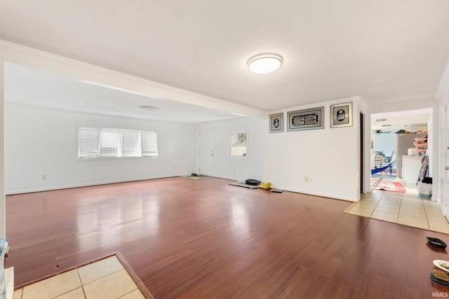 spare room with baseboards, light wood-style flooring, and a textured ceiling